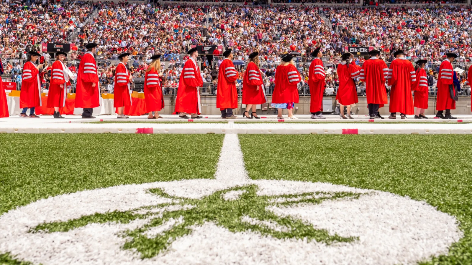 worms eye view of PhDs crossing field during commencement