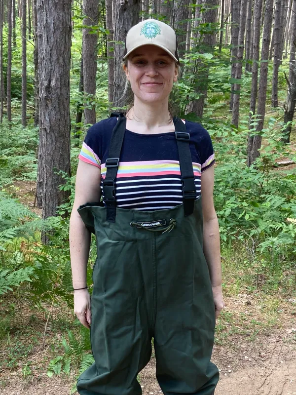 Erin Lindstedt in chest waders and ball cap outside in woods