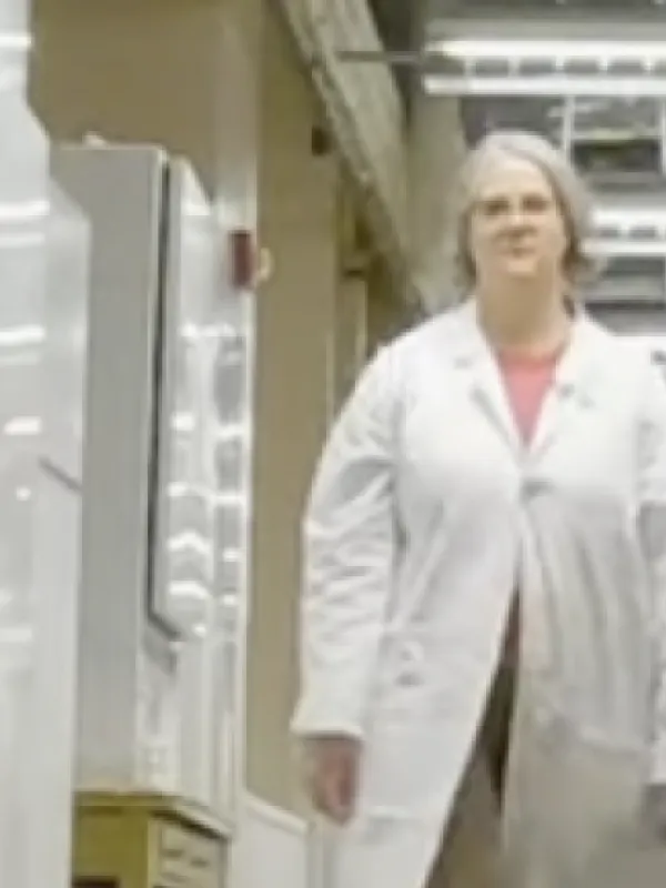 julie Reynolds walking down lab corridor wearing white lab coat