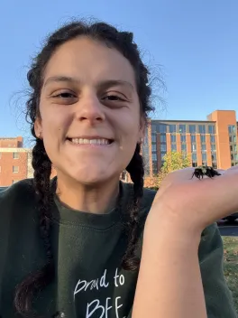 Lizzy sakulich holding bee outside in raised hand